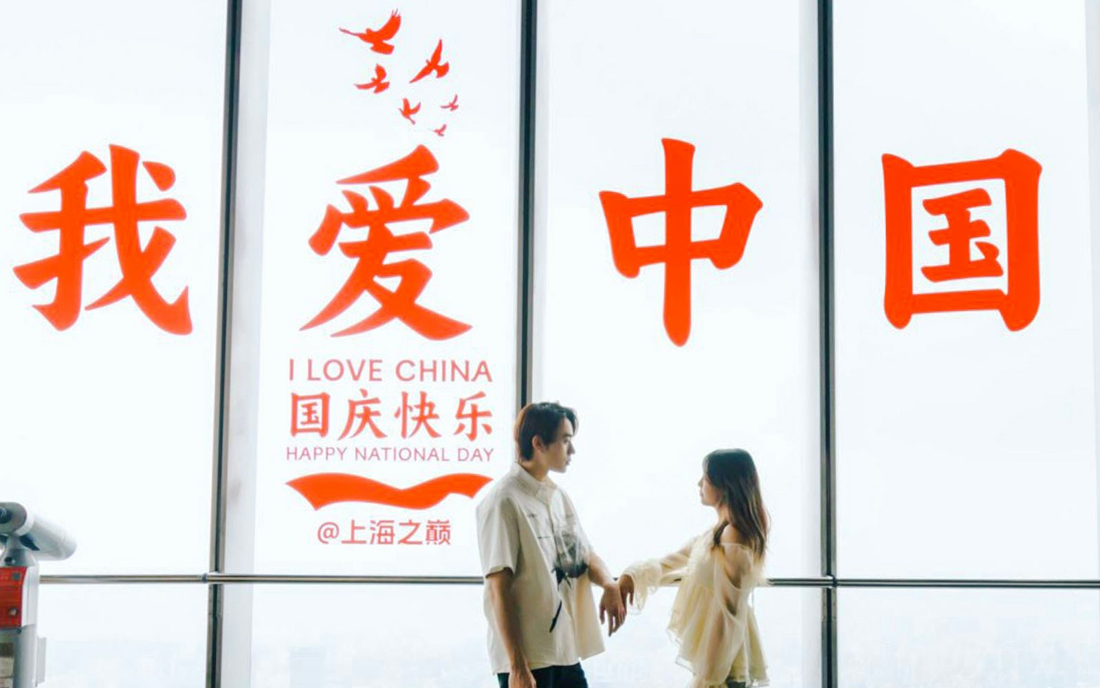 Couple standing inside Shanghai Tower with "I Love China" sign in background.
