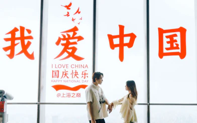Couple standing inside Shanghai Tower with "I Love China" sign in background.