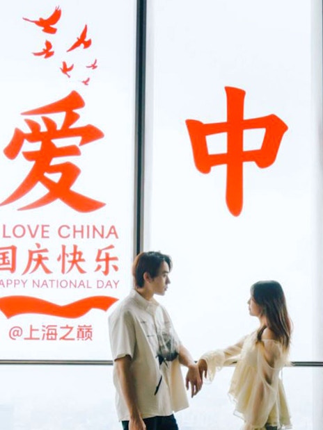 Couple standing inside Shanghai Tower with "I Love China" sign in background.
