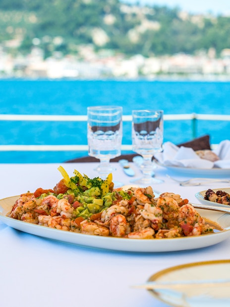 Seafood lunch on a cruise ship with view of Agistri and Aegina islands in the background.