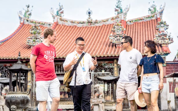 Tour guide with group at Penang temple during street food tour.