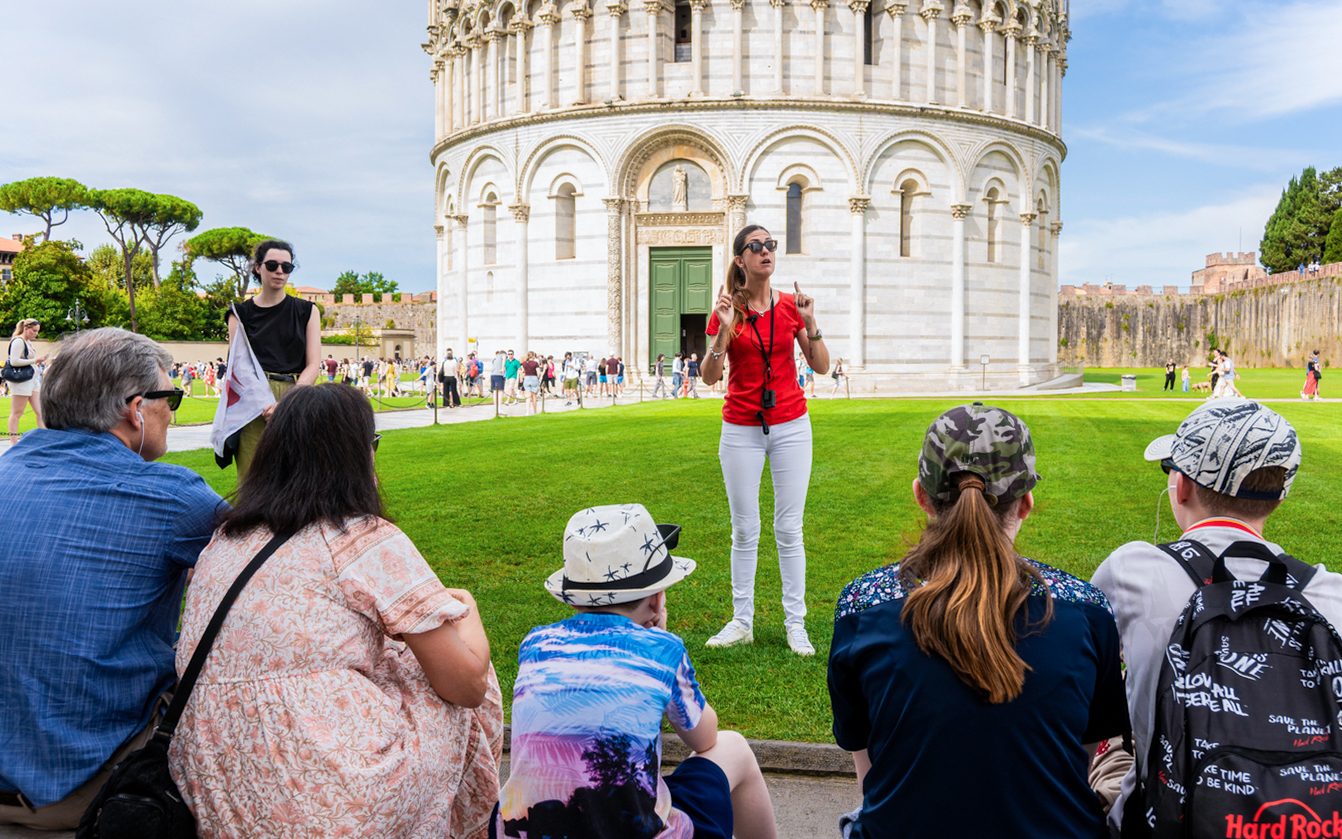 Guide leading tourists at the Tower of Pisa Complex, Italy.
