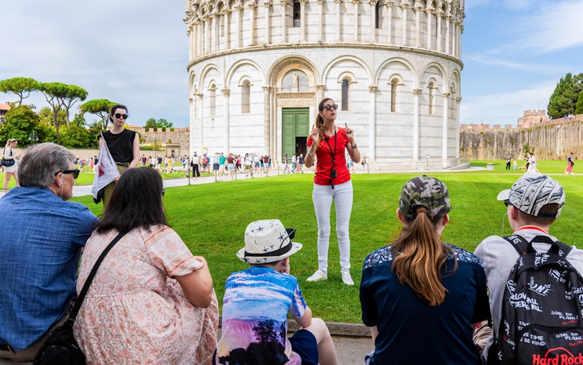 Guide leading tourists at the Tower of Pisa Complex, Italy.