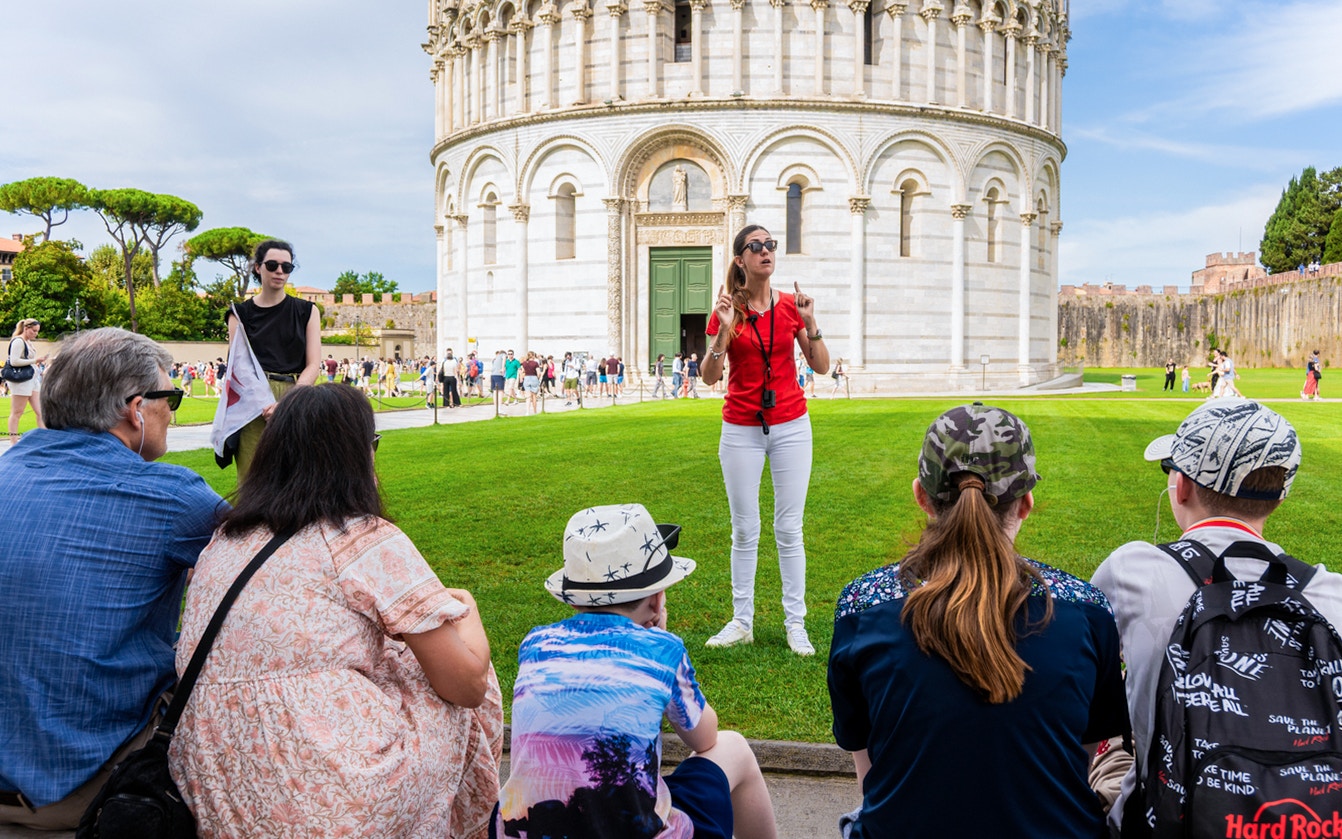 Guide leading tourists at the Tower of Pisa Complex, Italy.