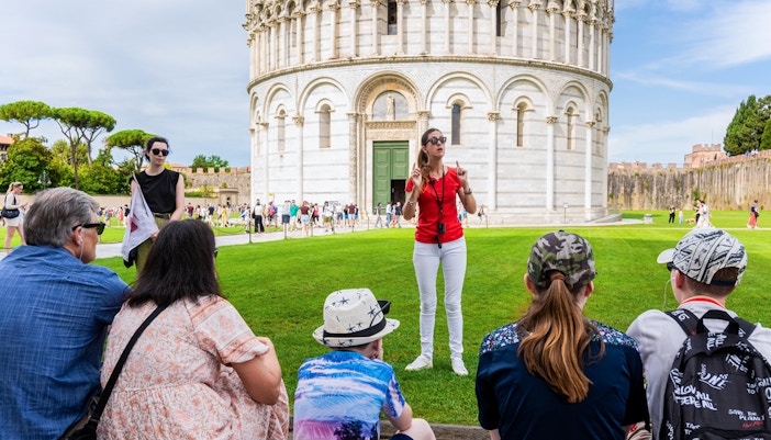 Guide leading tourists at the Tower of Pisa Complex, Italy.