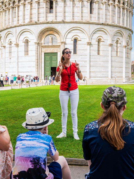Guide leading tourists at the Tower of Pisa Complex, Italy.