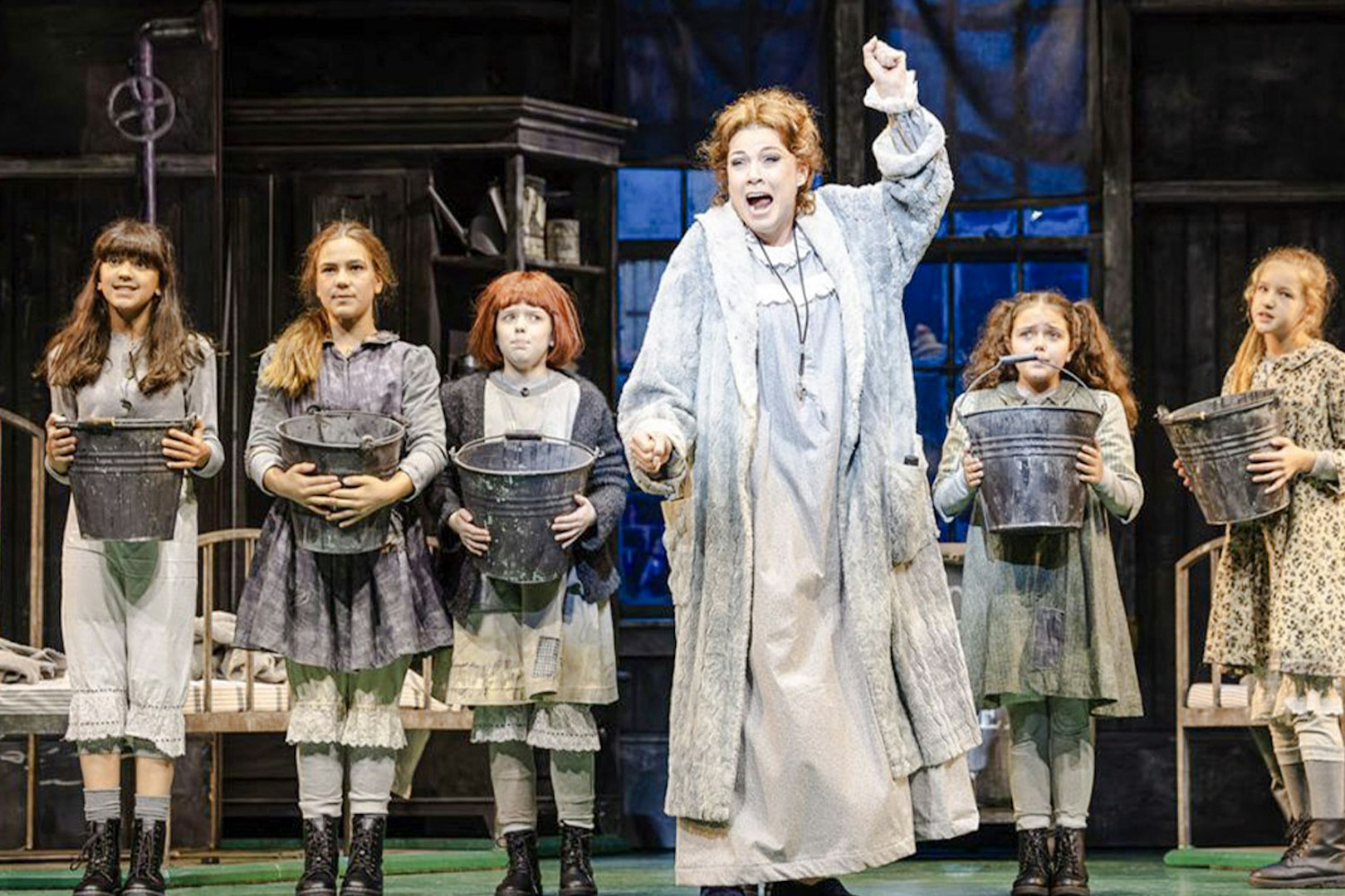 Children holding buckets on stage during an Annie performance.
