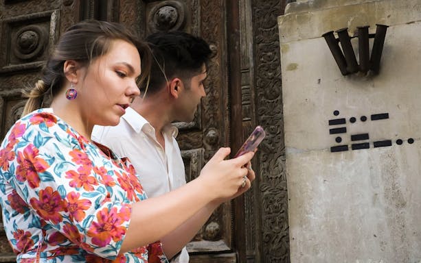 Participants using a smartphone for a city exploration game in Bordeaux Old Town.