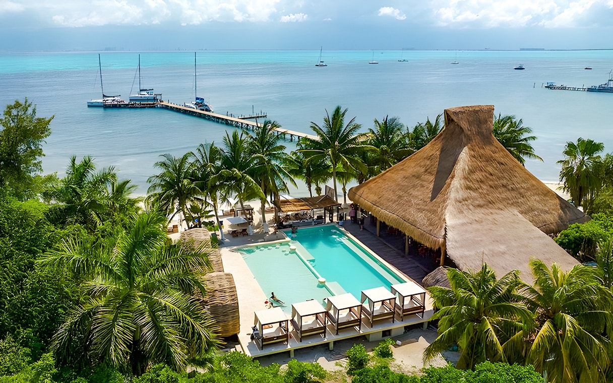 Zaza Beach Club on Isla Mujeres, Mexico with pool, palm trees, and ocean view.