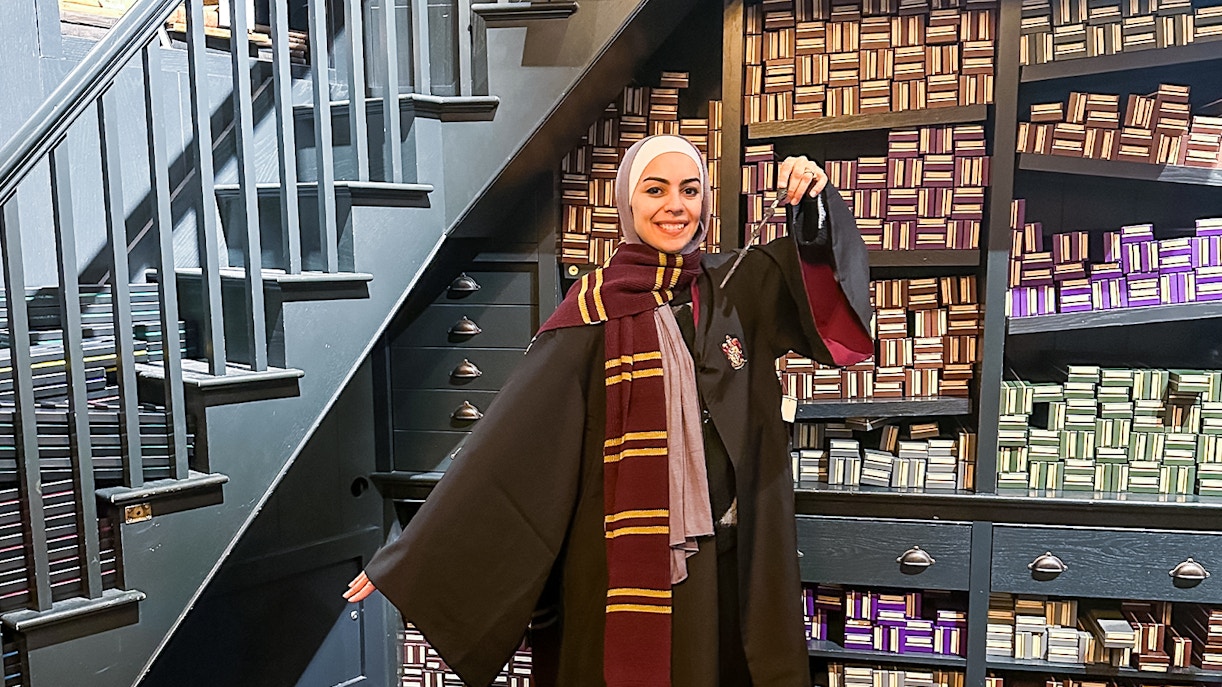 Visitor in wizard robe holding wand at Harry Potter London tour.