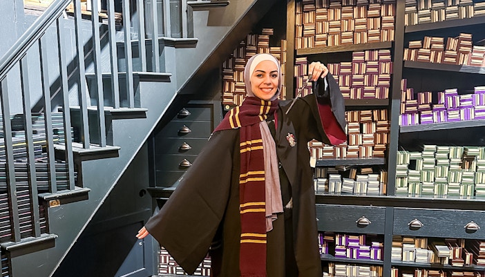 Visitor in wizard robe holding wand at Harry Potter London tour.