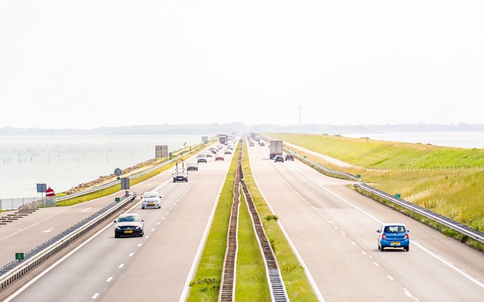 Afsluitdijk highway with cars driving between the IJsselmeer and Wadden Sea in the Netherlands.