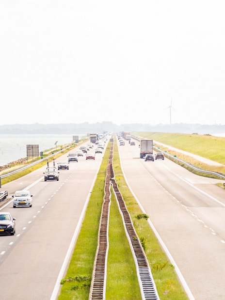 Afsluitdijk highway with cars driving between the IJsselmeer and Wadden Sea in the Netherlands.