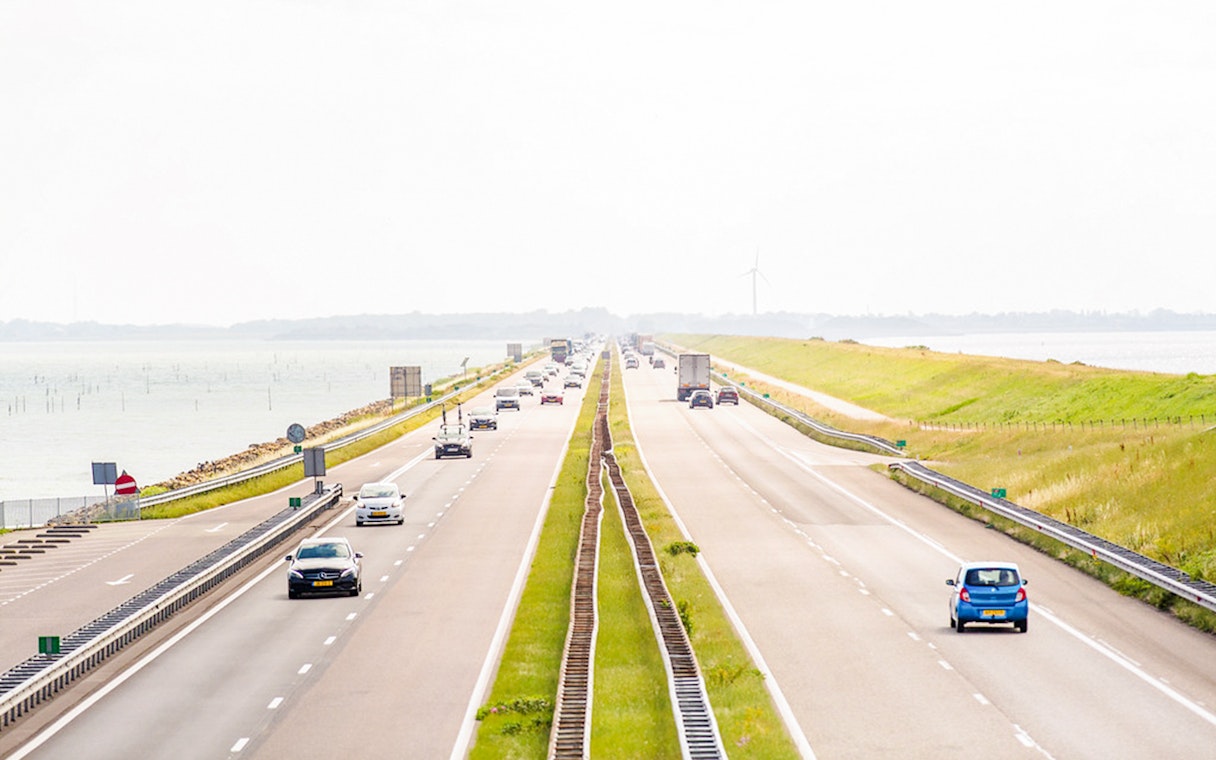 Afsluitdijk highway with cars driving between the IJsselmeer and Wadden Sea in the Netherlands.