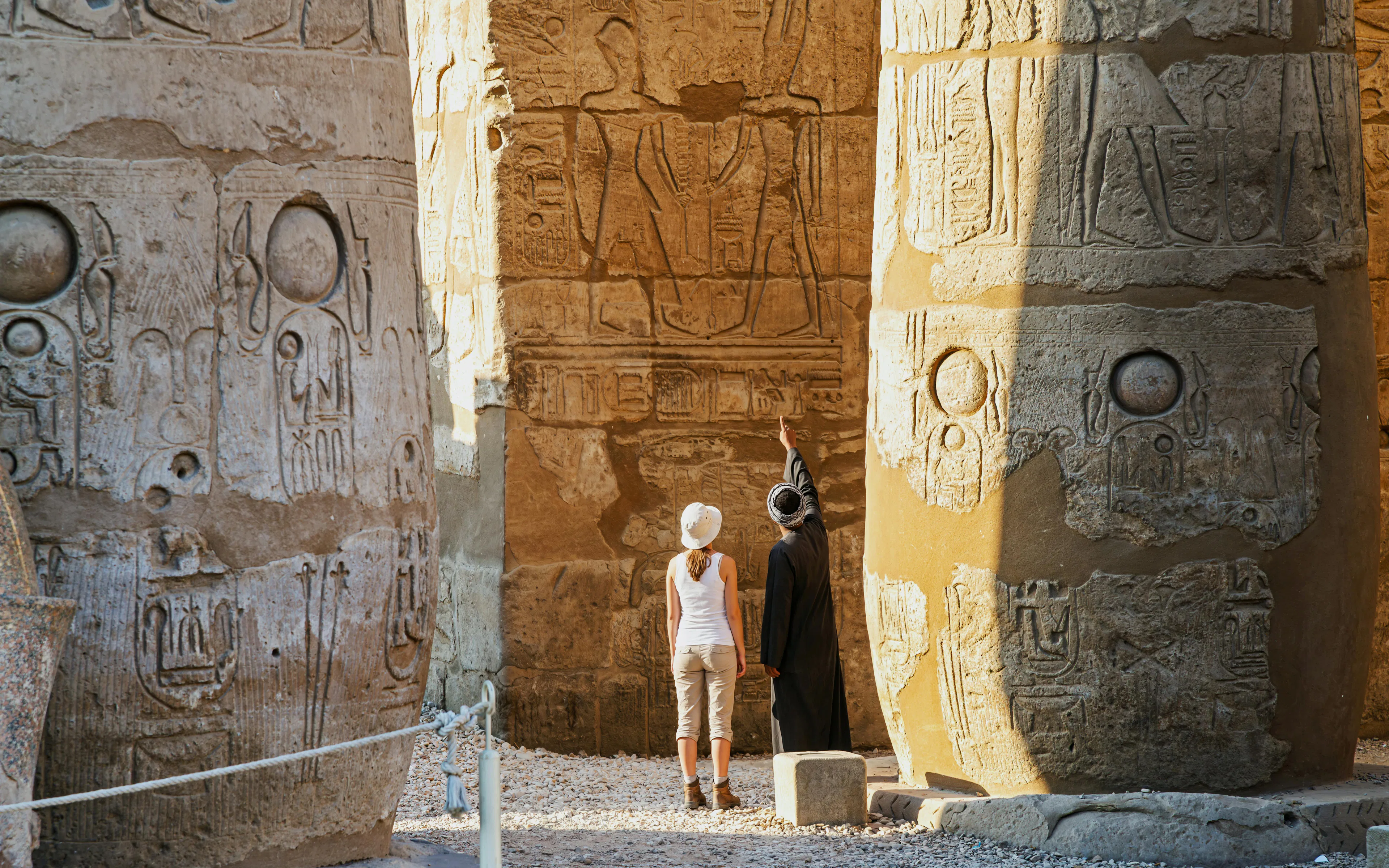 Private guide and tourist explore sandstone columns at Karnak Temple, Luxor, Egypt.