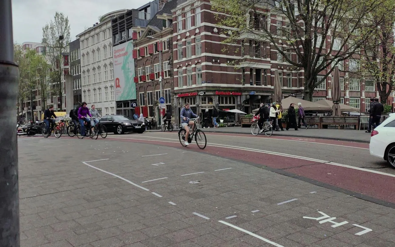 Cyclists and pedestrians near Rembrandt Corner in Amsterdam.