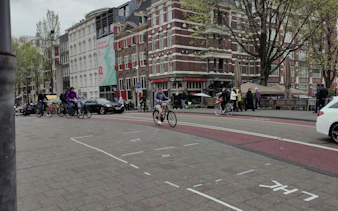 Cyclists and pedestrians near Rembrandt Corner in Amsterdam.