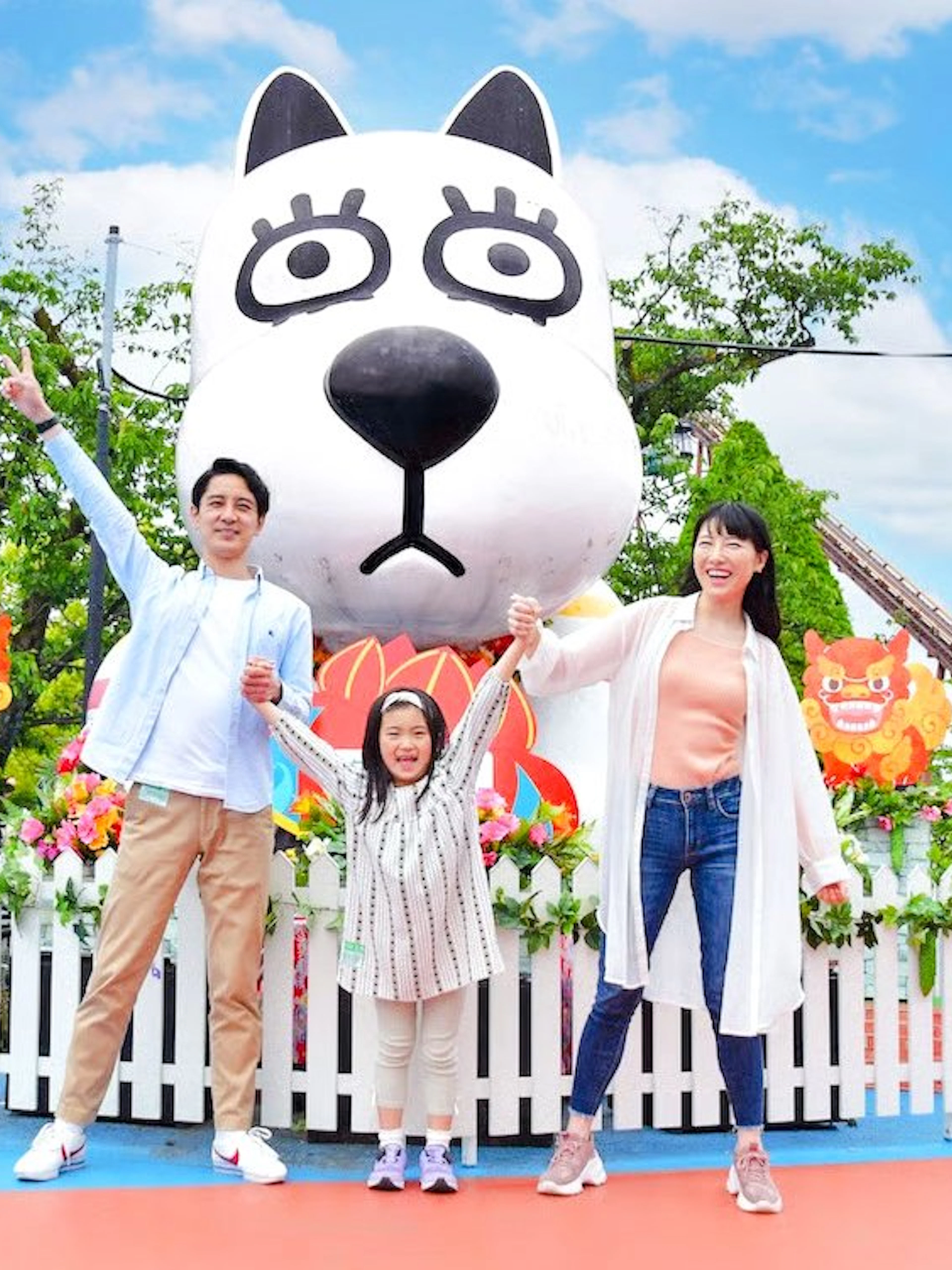 Family enjoying Yomiuriland amusement park in Tokyo with a large cartoon character statue.