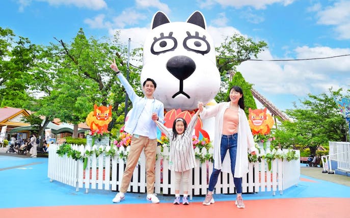 Family enjoying Yomiuriland amusement park in Tokyo with a large cartoon character statue.
