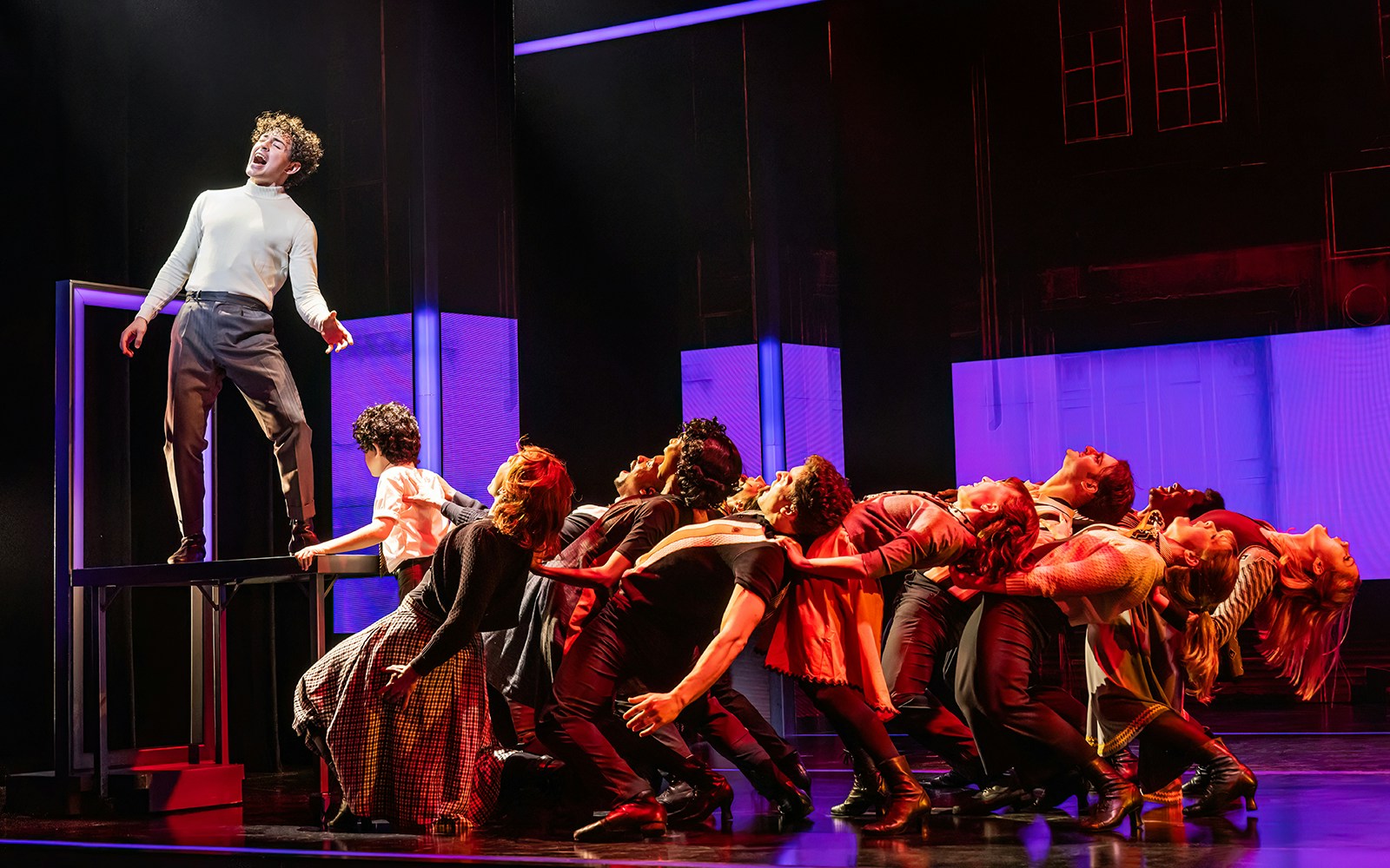 Cast performing a dynamic scene from The Who’s Tommy musical on stage.