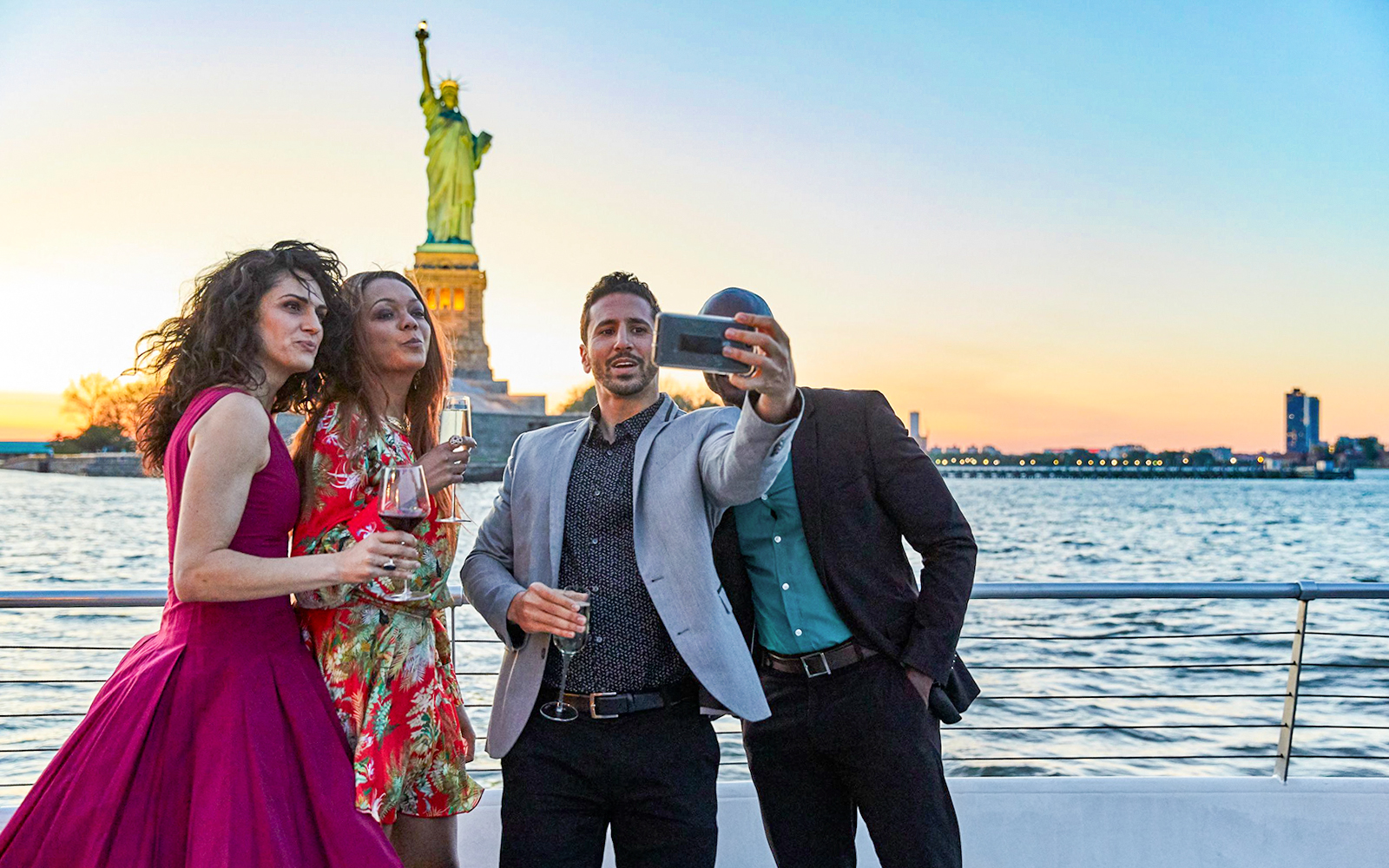 Group taking a selfie on Bateaux New York Premier Dinner Cruise with Statue of Liberty in background.