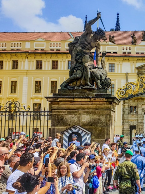 Ceremony at Prague Castle entrance with guards and crowd gathered.