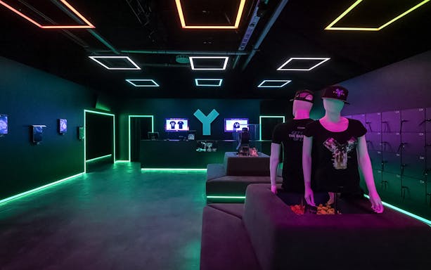 YULLBE GO VR Experience entrance with neon lights and mannequins in futuristic setting.