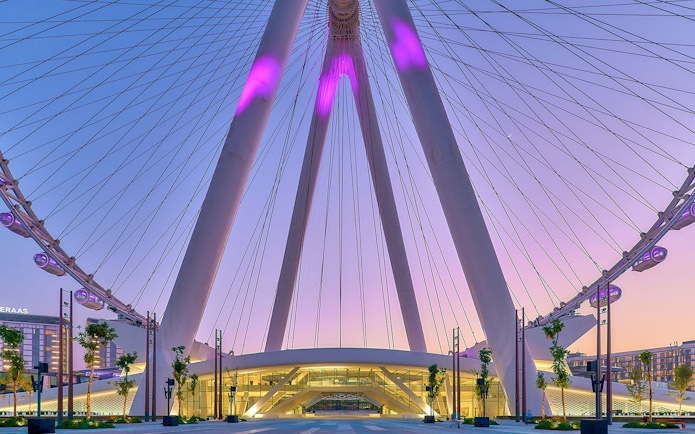 Ain Dubai Ferris wheel at sunset, Dubai skyline in background.
