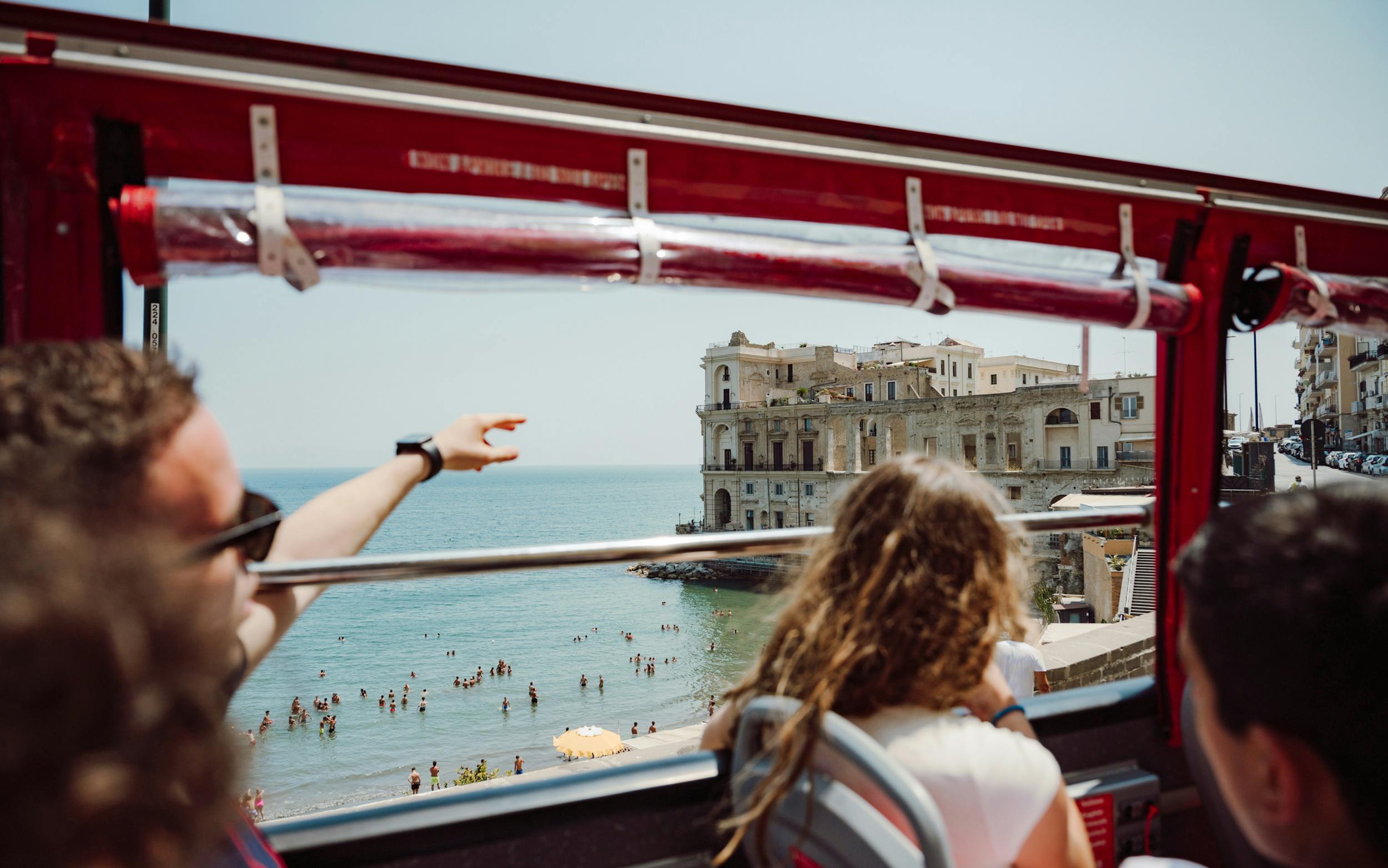Naples hop-on hop-off bus view of seaside and historic building.