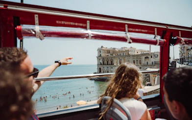 Naples hop-on hop-off bus view of seaside and historic building.