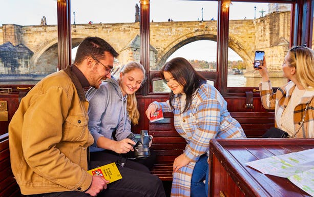 Tourists enjoying a boat ride with views of Charles Bridge in Prague, using the 72-hour visitor pass.