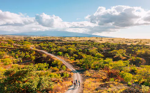 Group walking on a trail through Maunakea's scenic landscape during the Summit & Stars Giveback Experience.
