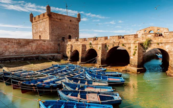 Sqala du Port in Essaouira with blue boats docked in the foreground.