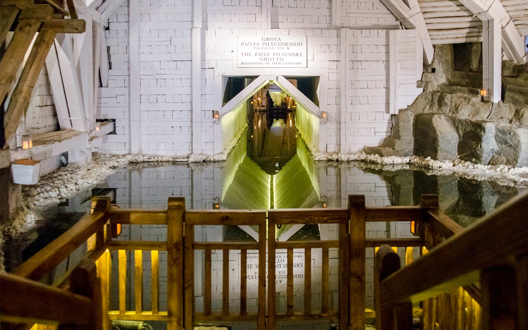 Wieliczka Salt Mine salt lake with wooden railing and illuminated tunnel entrance.