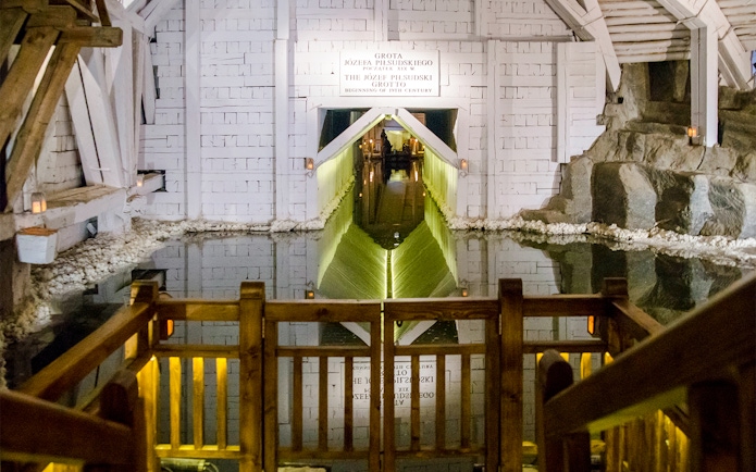 Wieliczka Salt Mine salt lake with wooden railing and illuminated tunnel entrance.