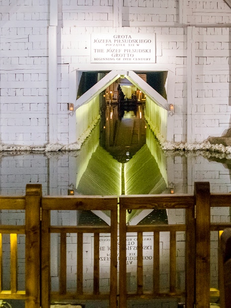 Wieliczka Salt Mine salt lake with wooden railing and illuminated tunnel entrance.