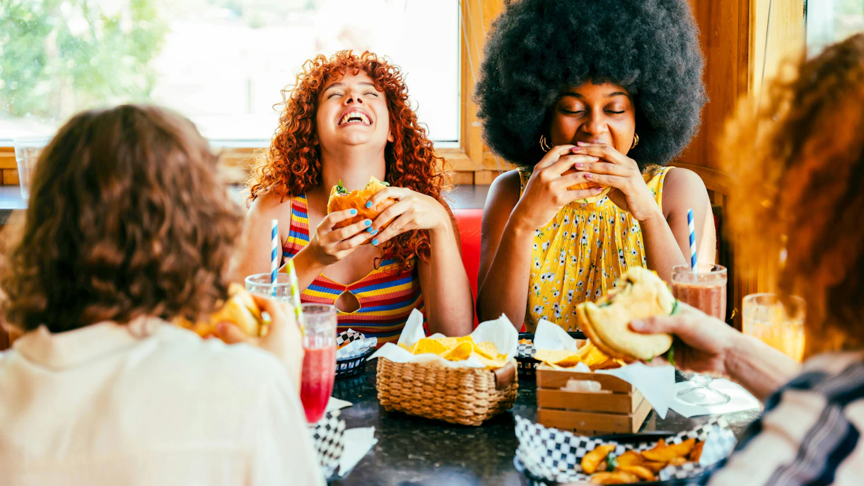 Friends enjoying burgers and drinks at a restaurant table.