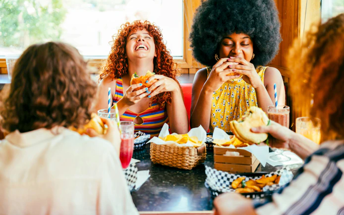 Friends enjoying burgers and drinks at a restaurant table.