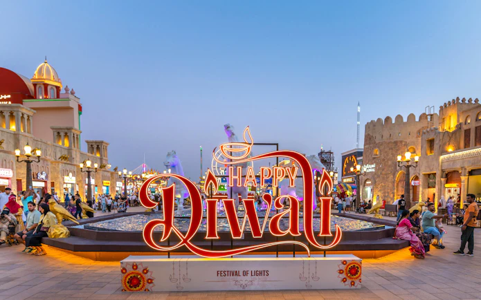 Global Village Diwali sign with festive lights and visitors in Dubai.