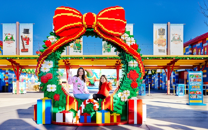 Visitors sitting in a LEGO Christmas wreath at Legoland New York.