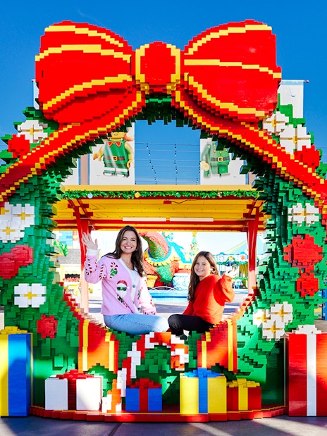 Visitors sitting in a LEGO Christmas wreath at Legoland New York.