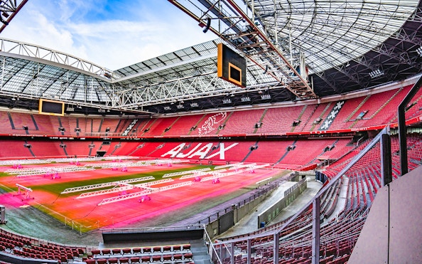 Johan Cruijff ArenA interior with empty red seats and field, Amsterdam.