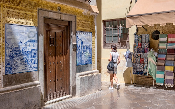 Street scene in Granada with traditional tiles and textiles near Alhambra.