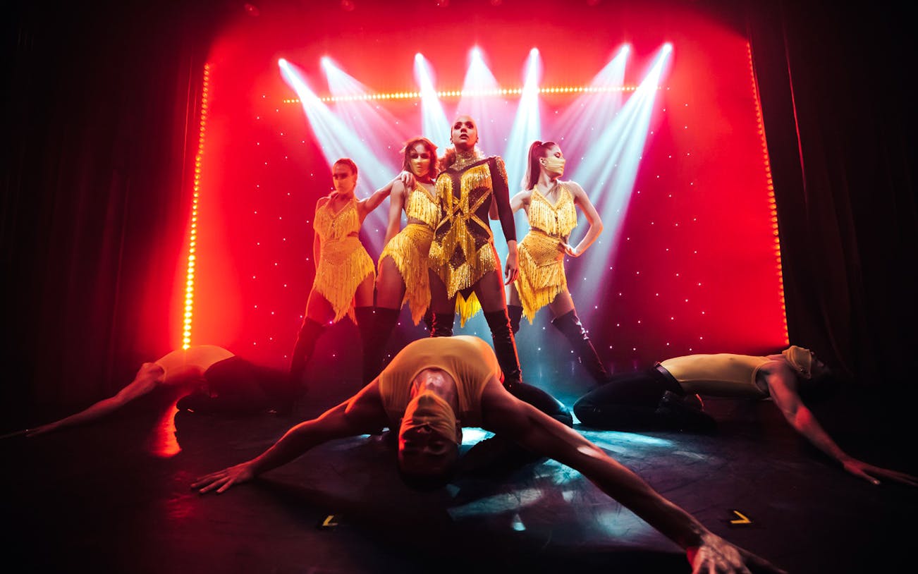 Performers in vibrant costumes on stage at Billionaire Dubai's luxury dining experience.