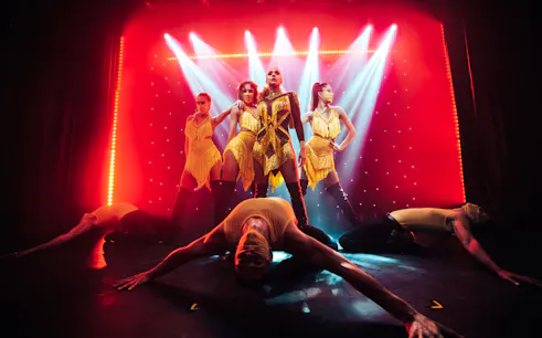 Performers in vibrant costumes on stage at Billionaire Dubai's luxury dining experience.