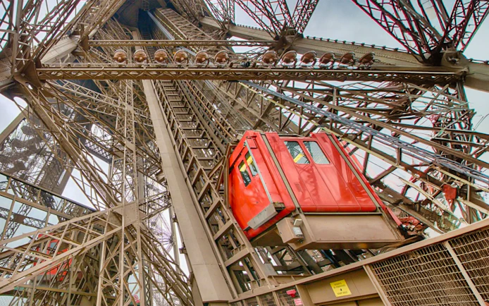 Eiffel Tower elevator ascending through iron structure in Paris.