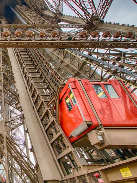 Eiffel Tower elevator ascending through iron structure in Paris.