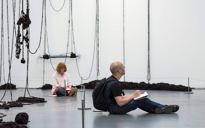 Visitors sketching art installations at Tate Modern, London.
