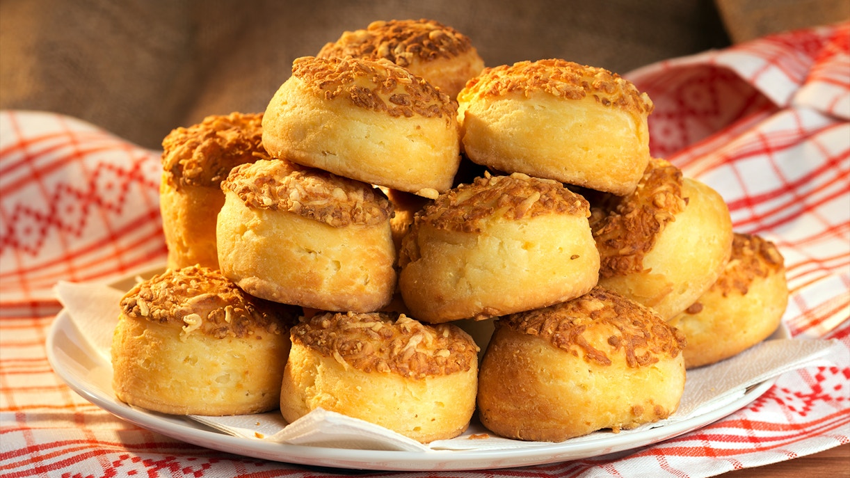 Traditional Hungarian cheese cakes, pogácsa, stacked on a plate with a patterned cloth.