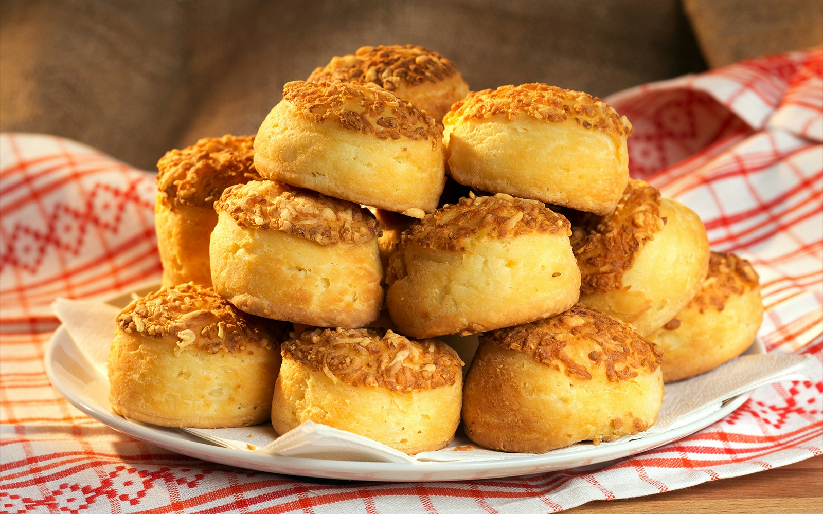 Traditional Hungarian cheese cakes, pogácsa, stacked on a plate with a patterned cloth.